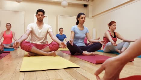 instructor assisting a group of people in yoga