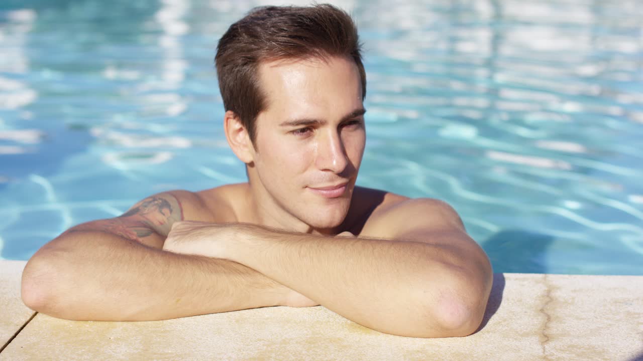 남자가 수영장에서 혼자 서서 카메라에 미소 짓고 있다