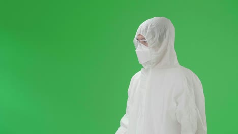 side view of angry asian man wearing personal protective equipment uniform ppe, medical face mask and pointing displeased and frustrated in the green screen studio
