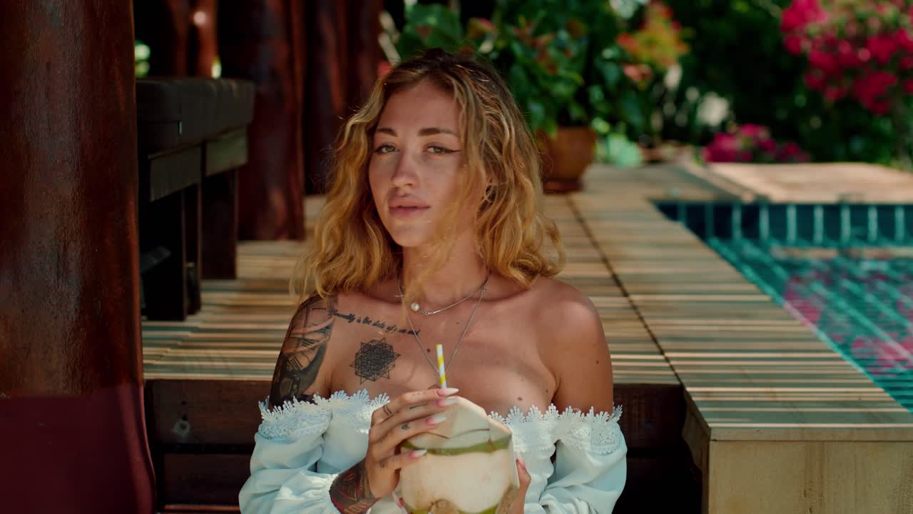 mujer relajándose junto a la piscina con un coco