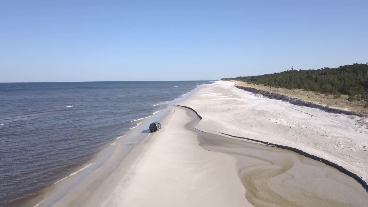Car driving along the seashore on the beach