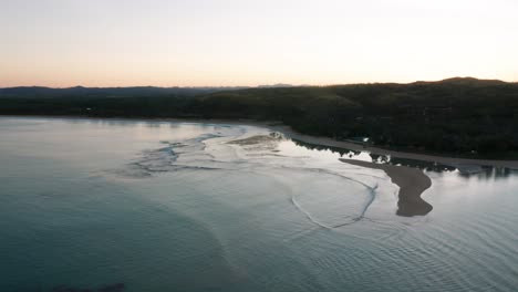 Bright-sky-during-sunrise-in-tropical-bay-in-Fiji-with-calm-seawater,-aerial