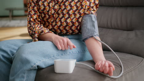 Closeup-of-woman-at-home-pressing-button-on-machine-to-start-blood-pressure-test