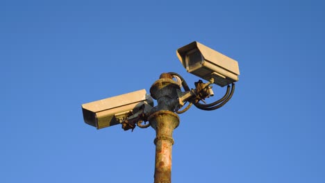 rusty old security cameras on a pole