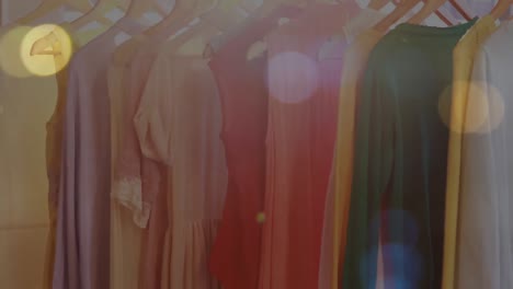 animation of bokeh lights over clothes hanging on display in shop