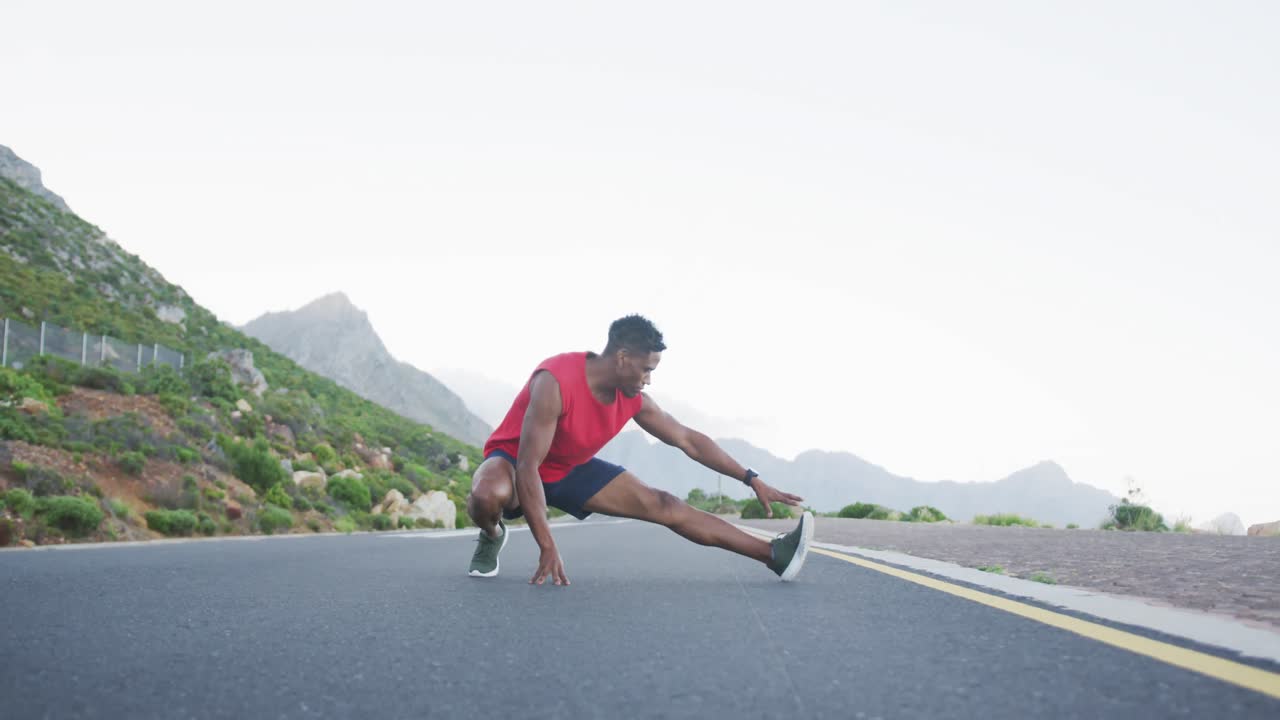 African american man performing stretching exercise on the road