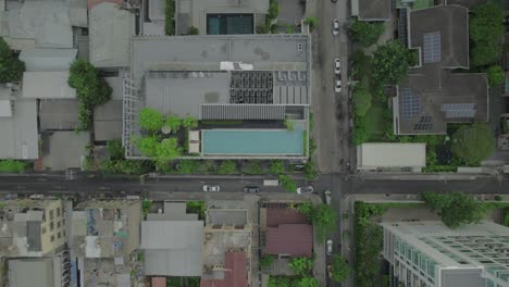 Bird's-eye-view-of-a-rooftop-with-pool,-tables-and-trees-in-a-building-in-Bangkok,-Thailand