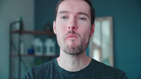 slow motion young caucasian man bites into burger at home, cheeseburger eating enjoyment, close up portrait fast food eating, unhealthy eating concept obesity
