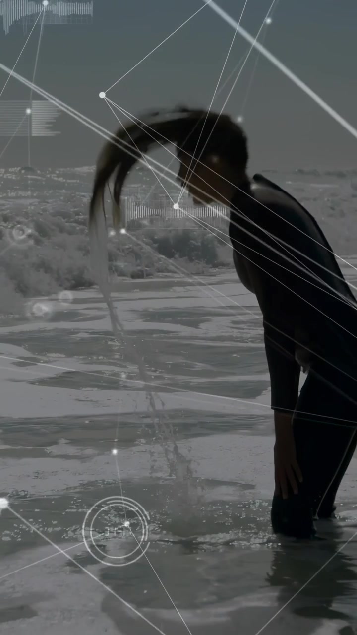 Vertikal video: Kvinne reiser seg og kaster på håret i bølgene, aktiverer teknologiske HUD-noder som sporer vannets bue.