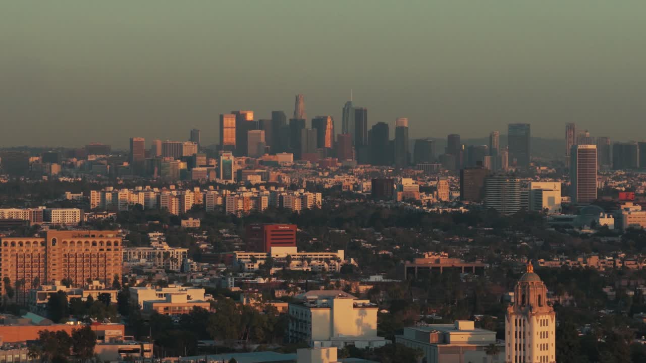 Ripresa aerea dolly con teleobiettivo della densa espansione urbana della città al tramonto a Los Angeles, California. 4K.