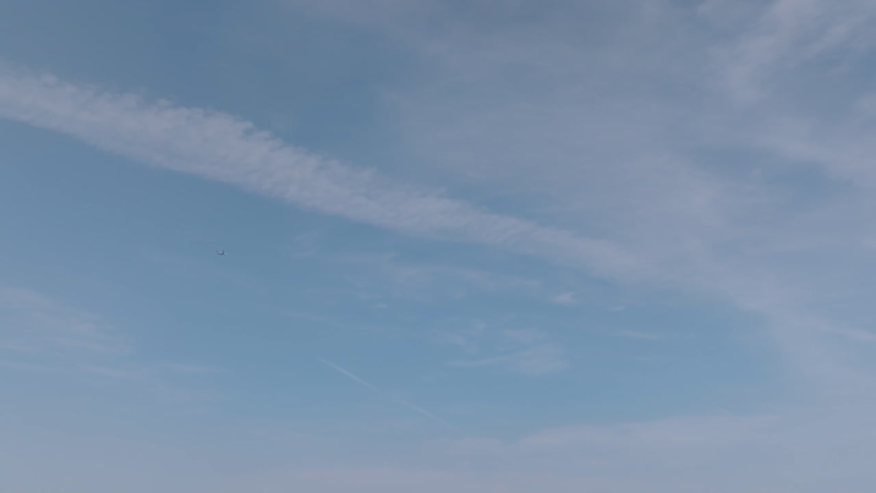 천천히 날아가는 여객기와 함께 구름이 흩뿌려진 하늘의 장면