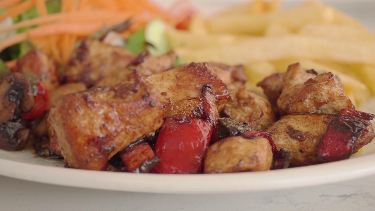 Close-up of Grilled Chicken with Red Peppers, French Fries, and Salad