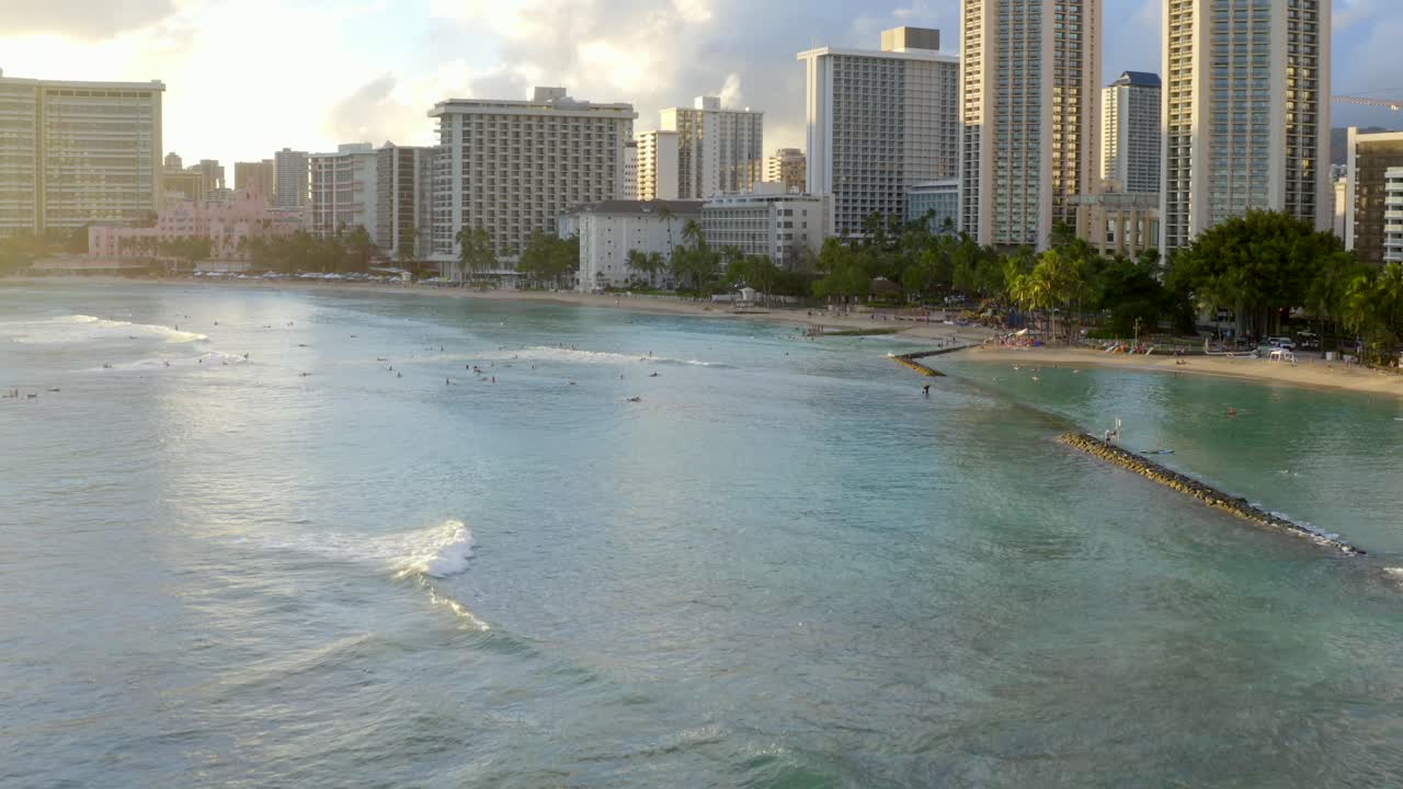 luz dorada golpeando la hermosa playa de waikiki mientras las olas pasan junto a los surfistas