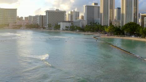 luz dorada golpeando la hermosa playa de waikiki mientras las olas pasan junto a los surfistas