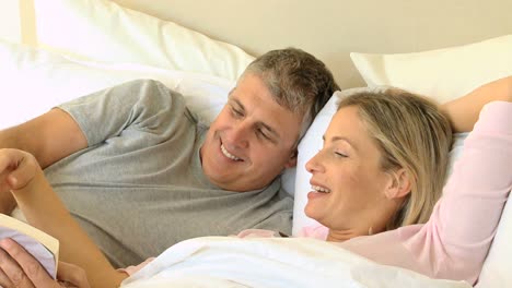 Couple-in-bed-sharing-a-book-and-laughing