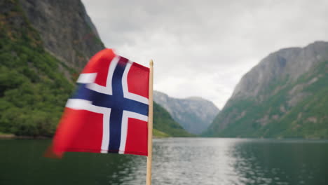 the norwegian flag flies in the wind against the backdrop of a majestic fjord cruise on the fjords o