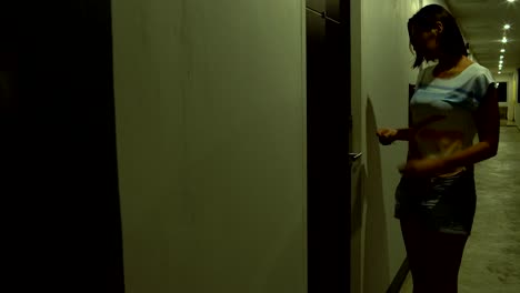 una mujer camina por el pasillo del hotel, aplica una tarjeta clave y entra en la habitación