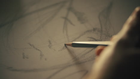 An artist draws a face on a sketch pad while sun illuminates the pad from a window