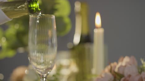 Close-Up-Of-Person-Pouring-Champagne-Into-Glass-At-Table-Set-For-Meal-In-Restaurant