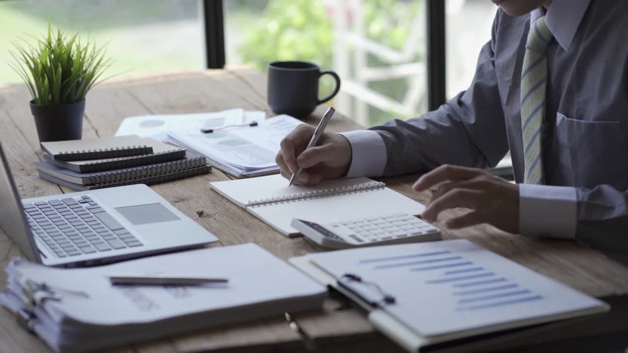 Businessman developing business project and analyzing marketing graph data with accounting documents and financial reports on 4k video table.