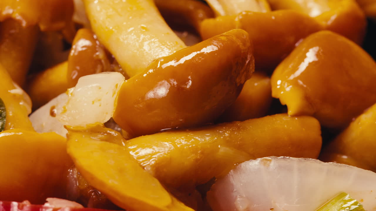 Close-up of fermented yellow honeydew mushrooms with onion on plate. Preservation of vegetables in glass jars. Fermentation preserved mushroom with spices rotating macro.