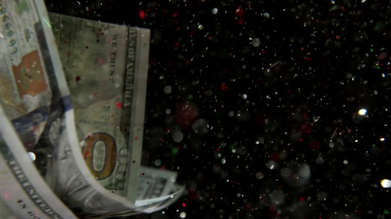 Falling flying american dollar banknotes and flying mixing with the glitter sparkles on a black background in 4K Loopable. High quality falling Dollar banknotes in 4K. Video is Loopable