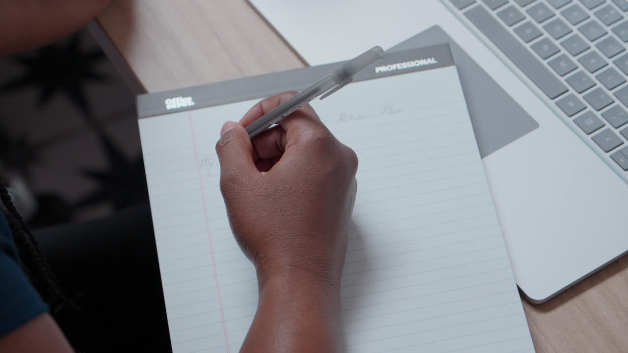 Primo piano di note e schizzi professionali disegnati a mano su un blocco note a righe accanto a un laptop in un moderno spazio di lavoro ufficio