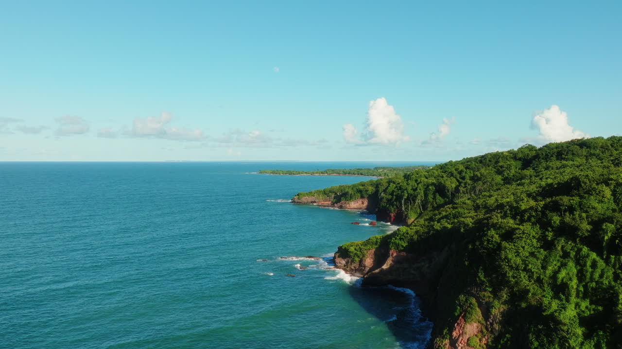 Drone che si alza e avanza lungo la costa di Guadalupa, superando una scogliera e rivelando la vasta isola tropicale