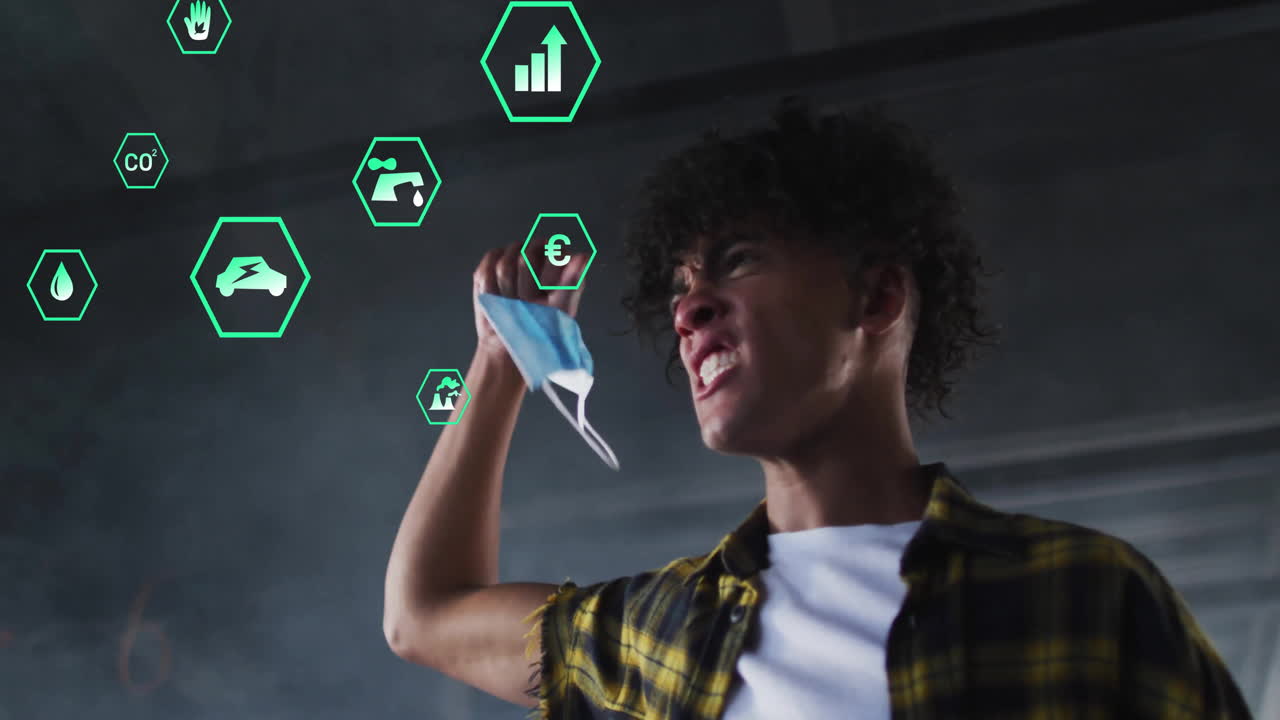 Man raising arm holding mask while shouting indoors, showing floating green hex environmental icons