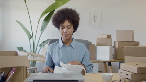 Young female entrepreneur packing purchased clothing