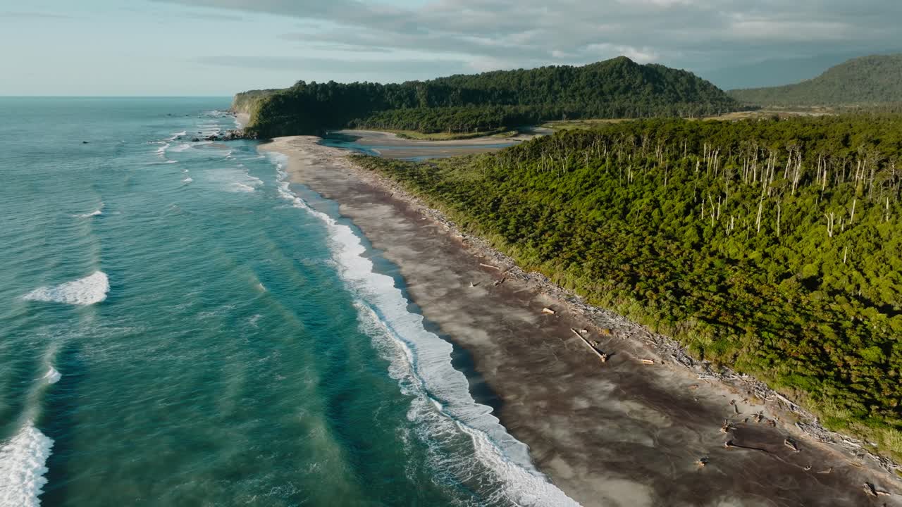 vista aerea selvaggia e accidentata di bruce bay paesaggio coperto da alberi, spiaggia coperta da legna galleggiante, foce del fiume e mare di tasmania nel sud-ovest della nuova zelanda