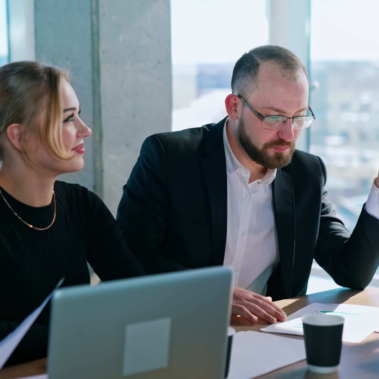 Partners for business indoors. Businessman and beautiful woman sitting together at the table in office room. Business meeting concept