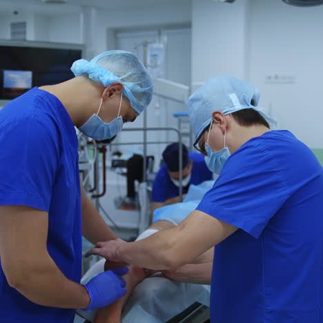operation on leg. medical specialists in blue uniform performing a surgery to a patient laying on surgical table in the modern operating theater