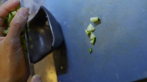 pepino recién cortado trasladado de la tabla de cortar en el tazón de ensalada usando la mano y el cuchillo, filmado como un primer plano vertical en estilo de cámara lenta