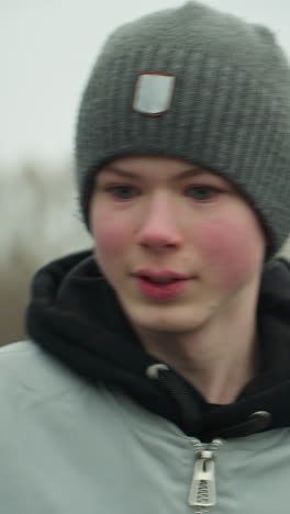 close-up of a young boy jogging on a track in a stadium, appearing focused from, the background is blurred, showing a football field