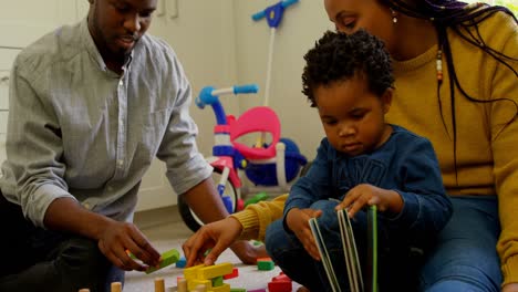 side view of young black parents and son playing and sitting on floor of comfortable home 4k