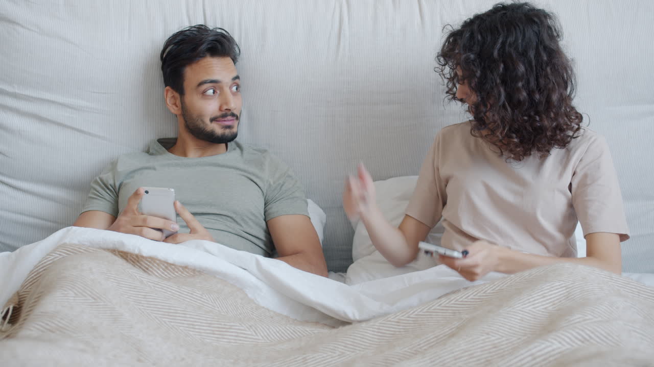 Couple in bed using smartphones