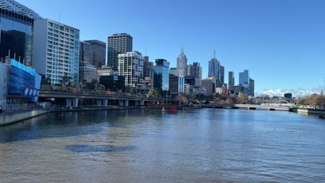 Die-Stadt-Melbourne-Blickt-Auf-Den-Fluss-Yarra,-Während-An-Einem-Sonnigen-Tag-Ein-Zug-Durchfährt