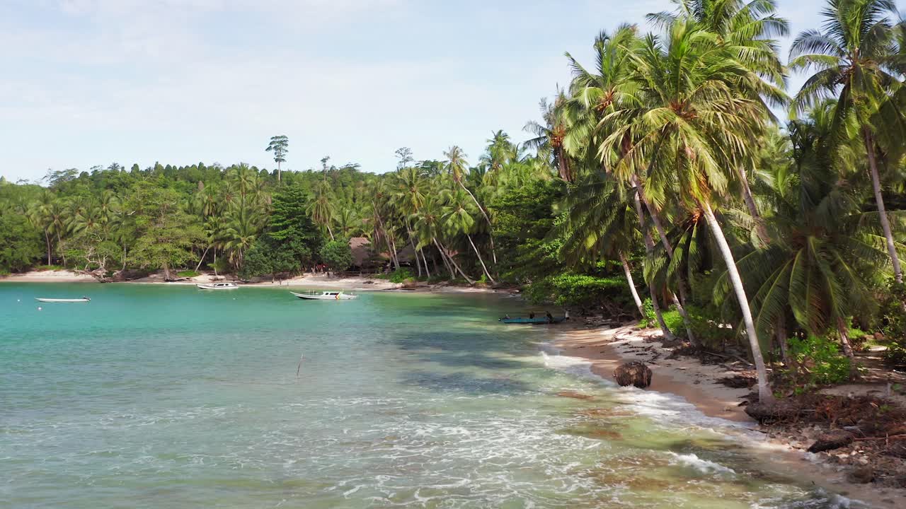 Aerial flight towards fishermen preparing boat by Indonesian palm beach lagoon