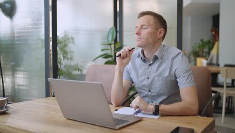 young thoughtful business man thinking of problem solution working on laptop. serious doubtful male professional looking away at laptop considering market risks making difficult decision