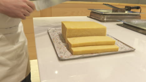 chef preparing and slicing a large block of pastry