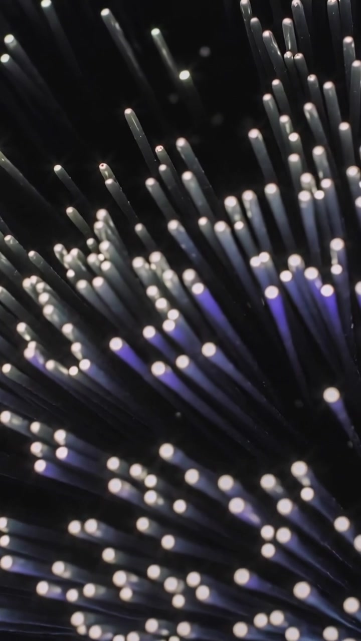 Vertical video: Shifting camera revealing glowing fiber bundle on table, green cord showing depth