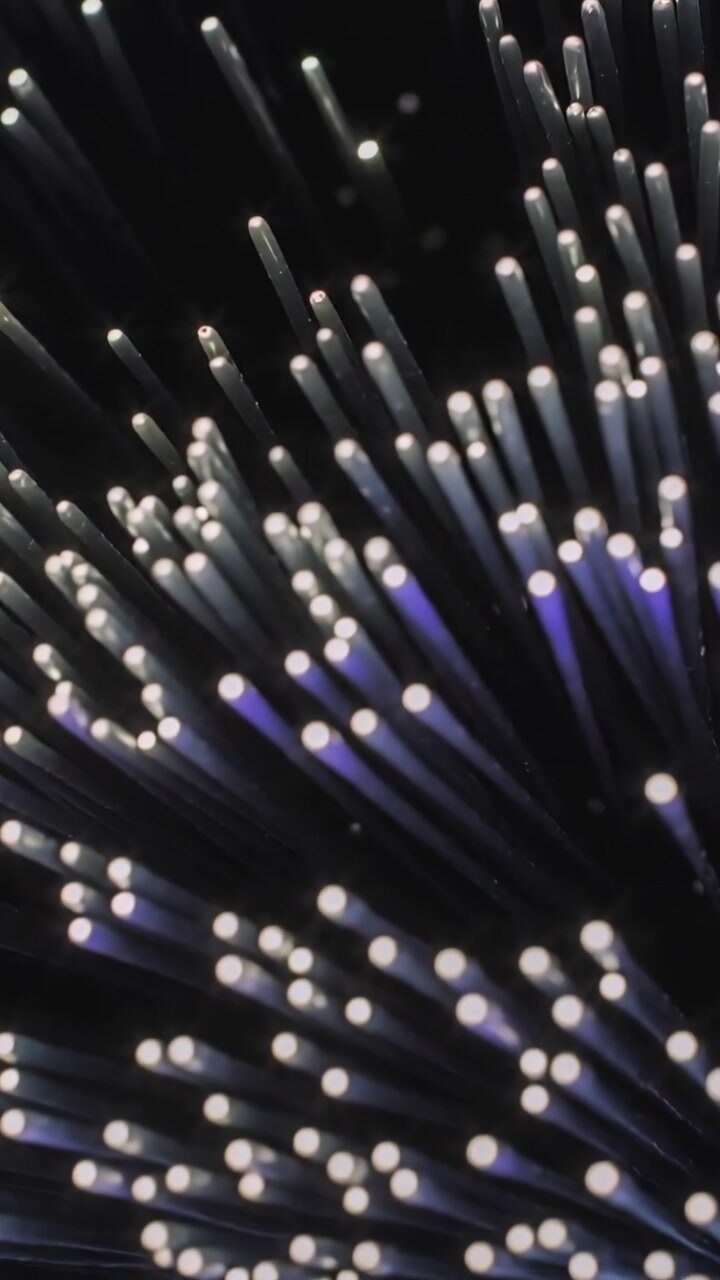 Vertical video: Shifting camera revealing glowing fiber bundle on table, green cord showing depth