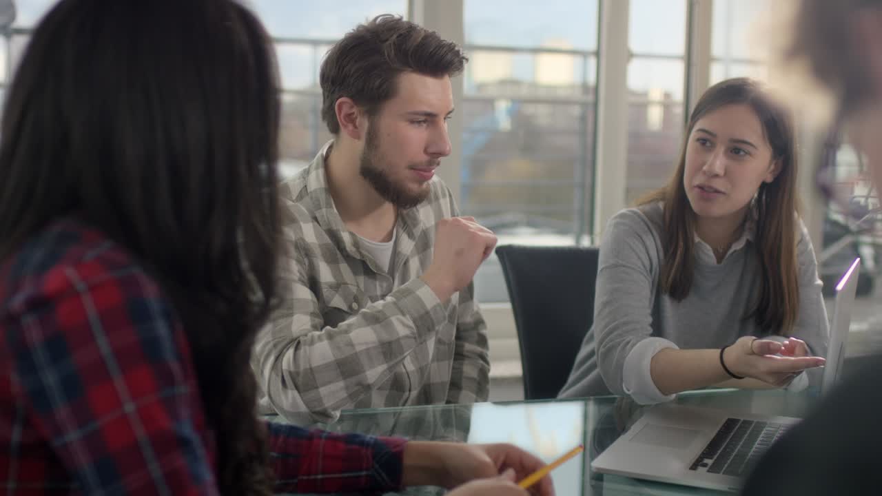 Office worker on laptop talking business to coworkers in new conference room
