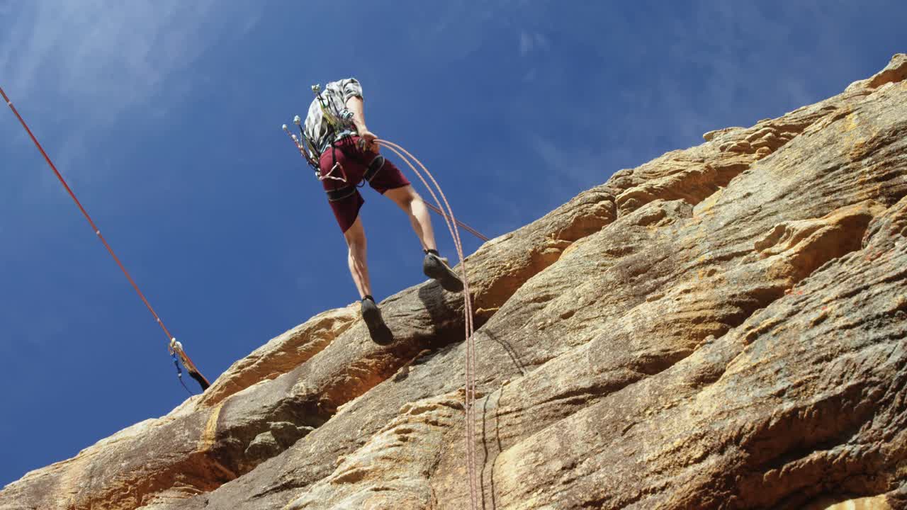 alpinista bajando en rappel por la colina con la ayuda de una cuerda 4k