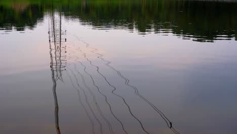 línea de alimentación de la red eléctrica de la torre de transmisión de toma amplia junto al lago sobre el reflejo de la montaña en el agua ondulante del lago