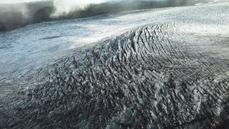 Aerial-landscape-view-through-clouds,-over-the-textured-ice-surface-of-an-icelandic-glacier