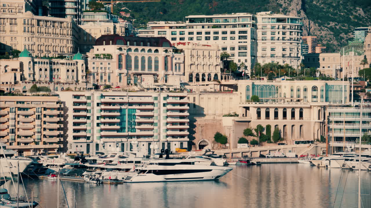 View of boats docked in the Monaco Marina with the skyline of the city on the background in the evening