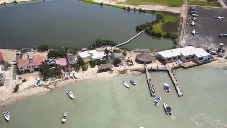 Pueblo-gran-roque-with-boats-and-airstrip-on-sunny-day,-los-roques,-venezuela,-aerial-view