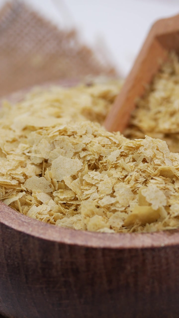 Nutritional Yeast Flakes in a Wooden Bowl with a Scoop